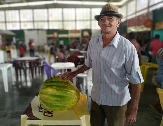 Agricultor ao lado de 'abóbora gigante' exposta na feira livre da cidade | Foto: Notícias de Santaluz 