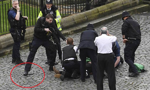 Policial aponta arma para suposto suspeito após ataque terrorista em Londres; faca usada no atentado pode ser vista no chão - Stefan Rousseau / AP