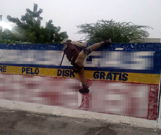 Policial pulando muro para ter acesso a terreno onde foram encontrados os pés de maconha | Foto: Divulgação/ PM