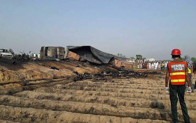 Socorrista observa corpos queimados depois que um caminhão-tanque sofreu acidente e pegou fogo no Paquistão (Foto: STR / AFP Photo