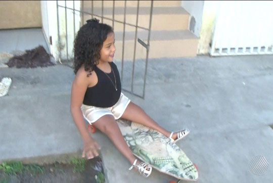 Com atrofia nas pernas e sem dinheiro para cadeira de rodas, menina de 8 anos usa skate para se locomover na Bahia