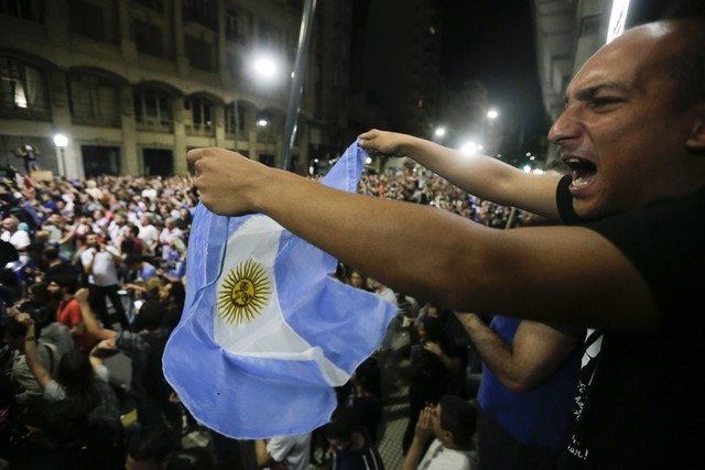 Manifestante segura bandeira da Argentina em protesto contra reforma previdenciária, em Buenos Aires, durante a madrugada desta terça (19) (Foto: Victor R. Caivano/AP Photo