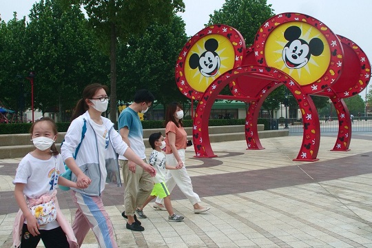 Visitantes com máscaras andam pelo parque temático da Disney em Xangai, nesta segunda-feira (11) | Foto: Sam McNei/AP